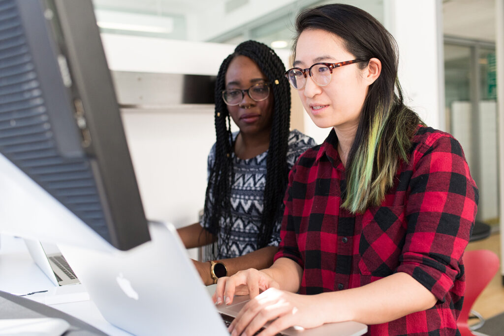 Asian woman and black woman working on computers