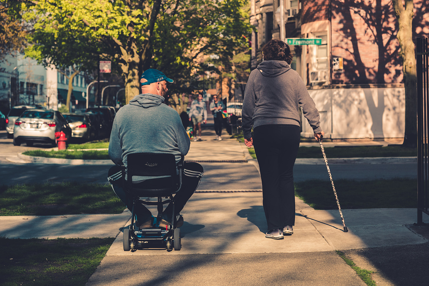 Man in electric wheelchair next to woman with cane.