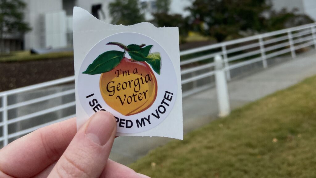 A hand holding a Georgia "I secured my vote" sticker.